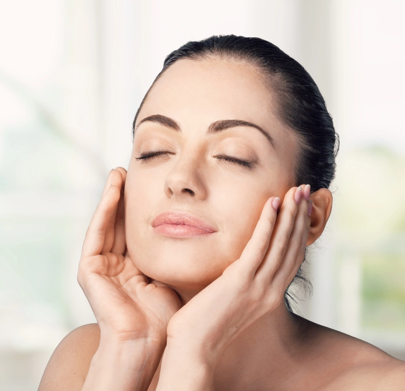 Woman with clear skin cradling her face with both hands, eyes closed
